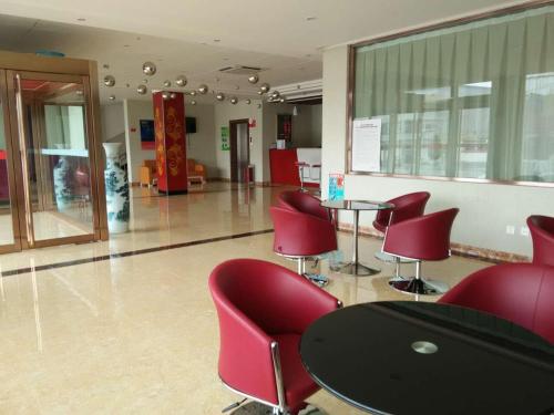 uma sala de espera com cadeiras vermelhas e uma mesa em Thank Inn Chain Hotel Shanxi Lvliang Jiaokou County West Street em Xiazhuang