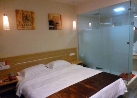 Thank Inn Chain Hotel Henan Puyang Taiqian Train Station في Dayuchen: غرفة نوم مع سرير ودش زجاجي