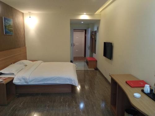 a bedroom with a bed and a desk and a television at Thank Inn Chain Shangdong Zaozhuang Tengjingzhou Jinghe Bridge Haishang Mingyue in Tengzhou