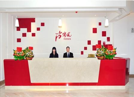 two people standing behind a counter in a room at Thank Inn Chain Hotel Guangdong Meizhou Mei County Lijiangwan in Meizhou