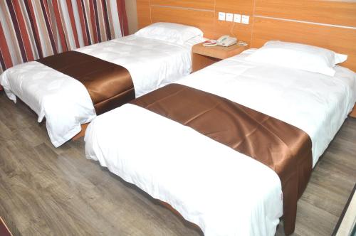a hotel room with two beds and a phone at Thank Inn Chain Hotel Shandong Qingdao Junfeng Road in Qingdao