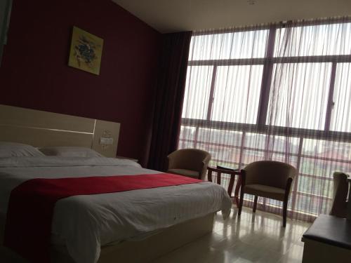 蘇州市にあるThank Inn Chain Hotel Jiangsu Suzhou Wujiang Pedestrian Streetのベッドルーム1室(ベッド1台、椅子2脚、テーブル付)