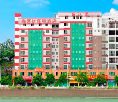 duży budynek z czerwonymi i zielonymi oknami obok wody w obiekcie Thank Inn Chain Hotel Guangdong Meizhou Mei County Lijiangwan w Meizhou