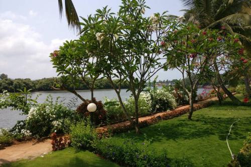 a garden with trees and flowers next to a body of water at Villa La Casita in Cavelossim