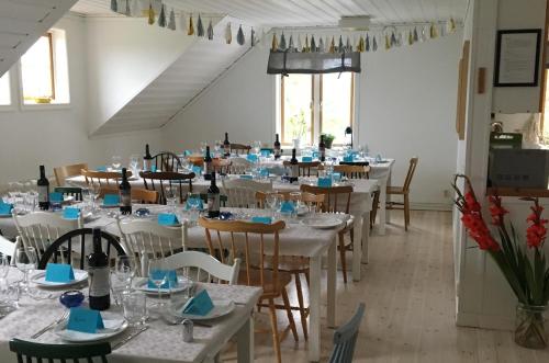 a dining room with white tables and chairs with blue napkins at STF Möja Vandrarhem in Möja