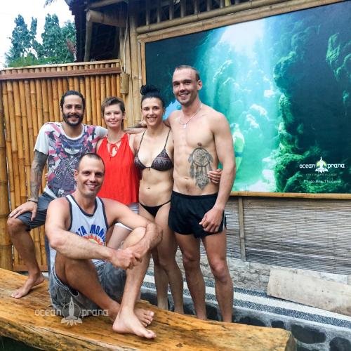 a group of people posing for a picture in front of an aquarium at Ocean Prana Village in Amed