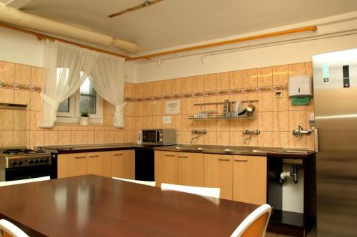 a large kitchen with a table and a refrigerator at Szkolne Schronisko Młodzieżowe w Gdańsku in Gdańsk