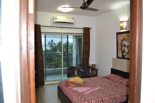 a bedroom with a bed and a view of a balcony at Ocean Shores Hospitality in Candolim