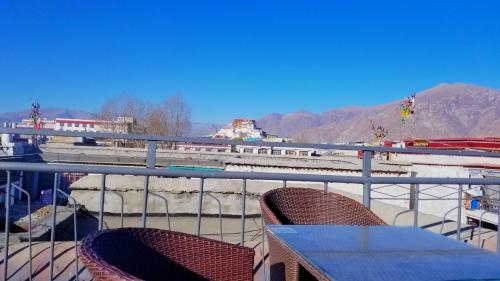 a table and chairs on a balcony with mountains at Fengma Feiyang Hostel in Lhasa