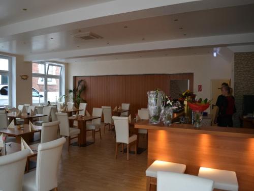 a dining room with tables and white chairs and a waitress at Altstadthotel-Rheine in Rheine