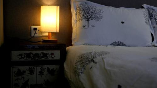 a bedroom with a bed with a lamp on a table at Fengma Feiyang Hostel in Lhasa