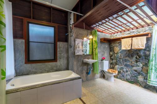 baño con bañera y pared de piedra en Kanya Cozy Bungalows Kata, en Kata Beach