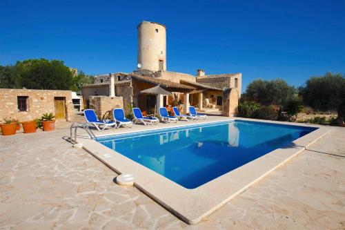 a pool in front of a house with blue chairs at Quality Villa Es Molí in Porreres