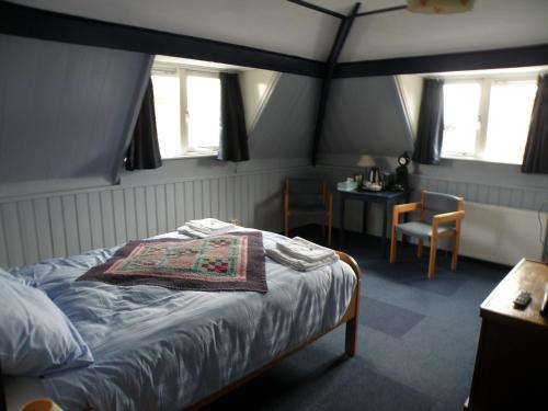 a bedroom with a bed and a table and windows at B & B Eindelinge in Serooskerke
