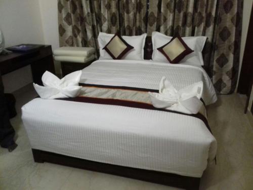 a bedroom with a large bed with white sheets and pillows at Iris Comfort Inn in Chennai