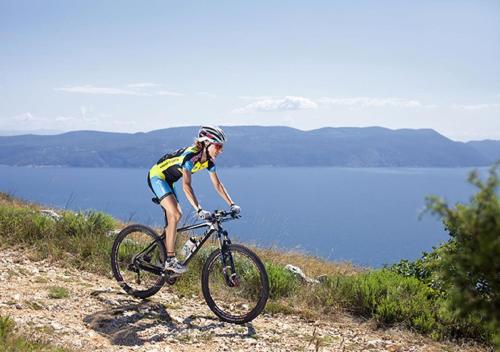 a person riding a bike on a hill near a body of water at Valamar Sanfior Hotel & Casa in Rabac