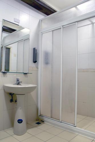 a white bathroom with a sink and a shower at Guest Motel- Zhongli Branch in Pingzhen