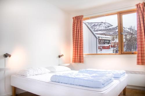 uma cama branca num quarto com uma janela em Geilolia Ferieleiligheter em Geilo