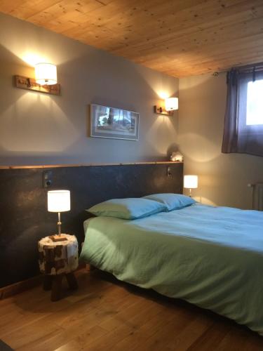 Les Fourgs的住宿－Au Charnet，一间卧室配有一张带蓝色床单的床和两盏灯。