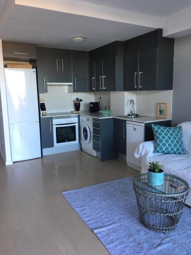 a kitchen with black cabinets and a white refrigerator at Beach flat with garden in Castelldefels