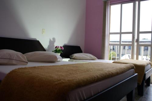 zwei Betten in einem Zimmer mit Fenster in der Unterkunft Hotel Manayara in Campo Largo