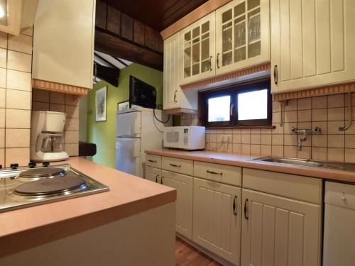 una cocina con armarios blancos y fregadero en detached chalet in lovely hiking region, en Bellevaux