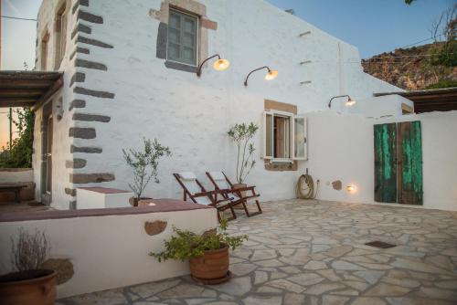 a patio of a white building with two chairs at Anemos Houses in Skala
