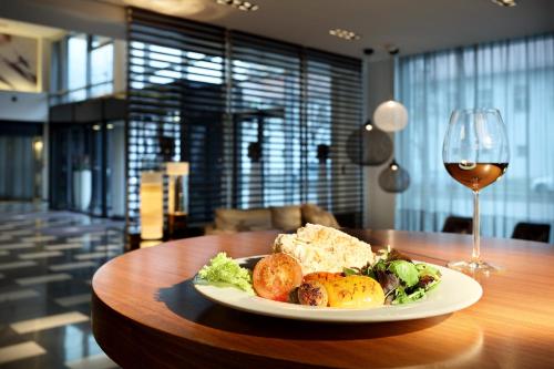 a plate of food and a glass of wine on a table at Eurostars Grand Central in Munich