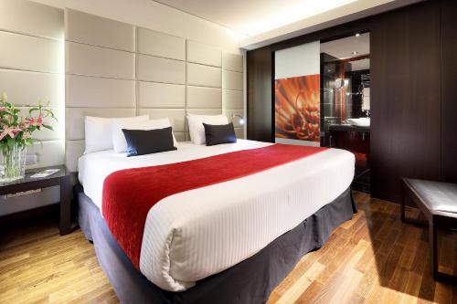 a hotel room with a large bed with a red blanket at Eurostars Grand Central in Munich