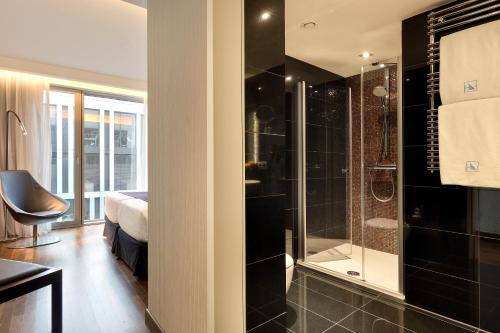 a bathroom with a shower and a bedroom with a bed at Eurostars Grand Central in Munich