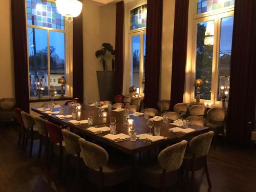 a long table in a room with chairs and windows at Villa Rubenshof in Helmond