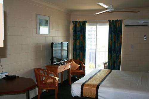 a room with a bed, desk, television and a chair at Luma Luma Holiday Apartments in Darwin