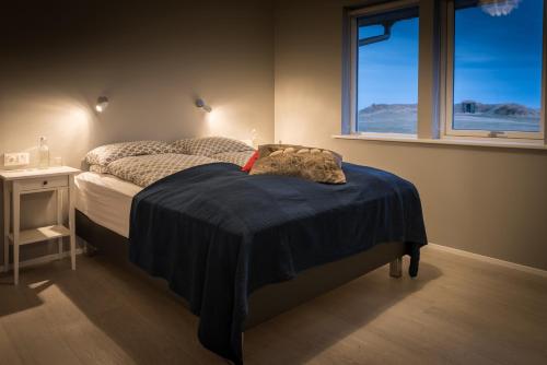 ein Schlafzimmer mit einem Bett mit einer blauen Decke darauf in der Unterkunft Bryggjur in Hvolsvöllur