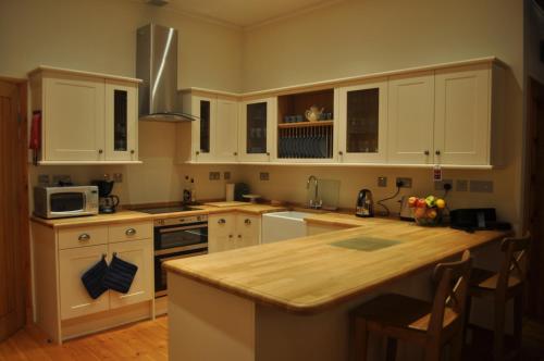 a kitchen with white cabinets and a wooden counter top at The Old Coach House, Alltshellach Cottages in North Ballachulish