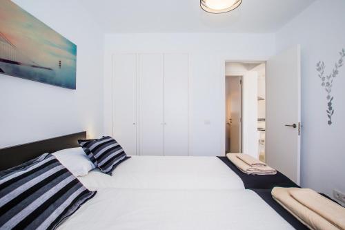 a bedroom with a large white bed with striped pillows at Flower Beach Suite 6 in Playa Honda