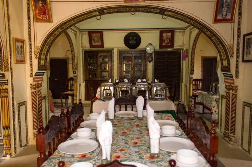 una sala da pranzo con un lungo tavolo con sedie e piatti di Narayan Niwas Castle a Rāmgarh