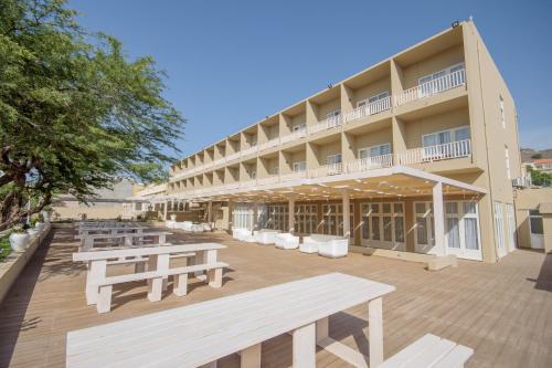 a building with benches and tables in front of it at Oasis Porto Grande in Mindelo