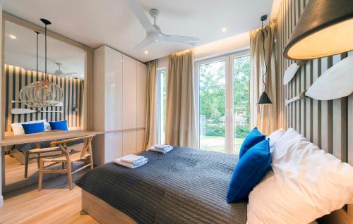 1 dormitorio con cama con almohadas azules y escritorio en Baltic Melody Apartament Pobierowo en Pobierowo