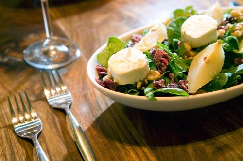 a salad in a bowl on a wooden table with forks at Southern Sun Newlands in Cape Town