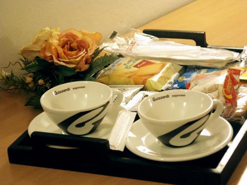 uma bandeja com duas chávenas e pratos numa mesa em B&B Zara em Milão