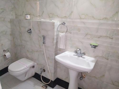 a white bathroom with a sink and a toilet at Hotel Executive Tower in Kolkata