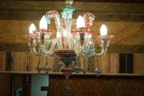 a glass chandelier with candles on a shelf at Hotel La Fenice et Des Artistes in Venice