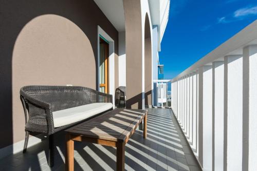 a wicker bench sitting on the balcony of a building at Hotel Biancaneve Wellness in Marotta