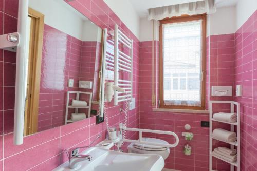 a pink bathroom with a sink and a toilet at Hotel Biancaneve Wellness in Marotta