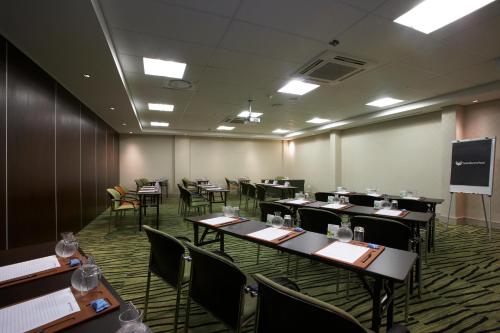 a conference room with tables and chairs and a screen at Southern Sun Newlands in Cape Town