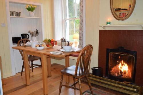 a dining room with a table and a fireplace at Glenbranter Cottage in Strachur