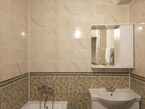 uma casa de banho com um lavatório, um espelho e uma banheira em Loftik Apartments Abay street em Almaty