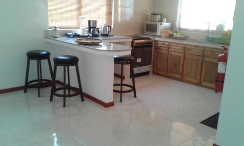 eine Küche mit Theke und zwei Barhockern in der Unterkunft Jbillaselfcatering in Beau Vallon