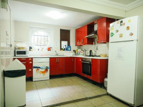 a kitchen with red cabinets and a white refrigerator at Deeps Hostel Ankara in Ankara