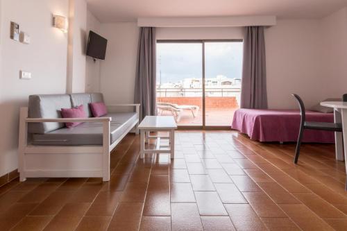 a bedroom with a couch and a bed and a balcony at Apartamentos Orosol 2 by Typic Hotels in San Antonio